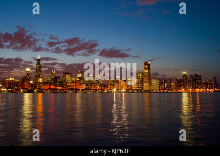 Ein warmer Frühling abends entlang des Lake Michigan Shore mit der berühmten Skyline von Chicago steigende über das ruhige Wasser. Stockfoto