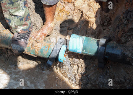 Klempner Arbeiter Reparatur der Wasserleitung gebrochen, Rohr, unterirdische Wasser auf Straße. Stockfoto