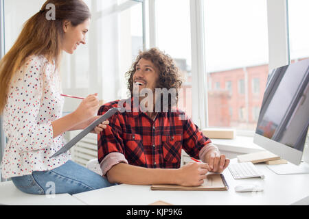 Glückliche junge Kollegen, die über neue Designtrends diskutieren oder die Arbeit im Büro organisieren Stockfoto