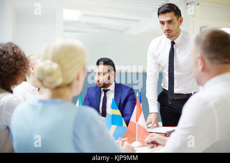 Ein junger Politiker zu mehr erfahrene Kollegen aus anderen Land am Seminar hören Stockfoto