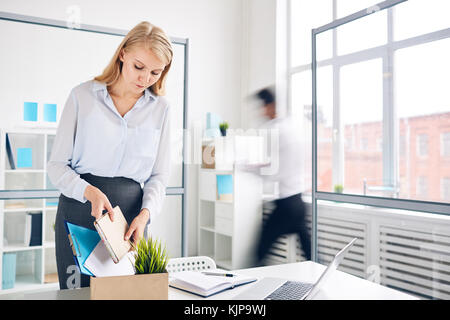 Neue Mitarbeiterin nimmt ihre Sachen aus der Box am Arbeitsplatz in der Büroumgebung heraus Stockfoto