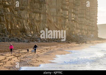 West Bay, Dorset, Großbritannien. Sonntag, 26. November 2017. Wetter in Großbritannien. Die Menschen genießen die Morgensonne beim Spaziergang am Strand. Credit: Sebastian Wasek/Alamy Live News Stockfoto