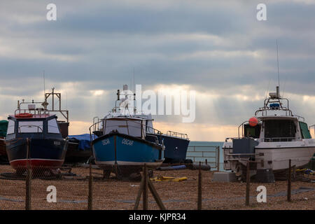 Hastings, East Sussex, UK. 29. November 2017. Schöne Anzeige der Sonnenlicht Piercing durch die Wolken weit draußen auf dem Meer, während mehrere Fischtrawler sitzen am Kieselstrand. Foto: Paul Lawrenson/Alamy leben Nachrichten Stockfoto