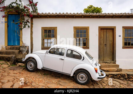 Weiße Kolonialhausfenster, weißer Volkswagen Käfer, Kopfsteinpflasterstraße, Tiradentes, Minas Gerais, Brasilien. Stockfoto