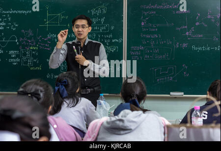 Asiatische Lehrer, die Lektion zu Gruppe Studenten, die die Frage in der Klasse Antwort über die Physik Formular in thailändischer Sprache auf Schwarz Stockfoto