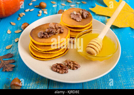 Duftende goldenen Kürbis Pfannkuchen mit Honig und Walnüssen auf einem blauen Hintergrund Holz. traditionellen amerikanischen Gericht Stockfoto