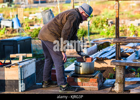 Vaxjo, Schweden - 13. November 2017: Dokumentation des Alltags und der Umwelt. Senior-Mann, der einen Stein auf den Topfdeckel im Kleingartenbereich legt. Er ist weich Stockfoto