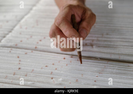 Hand mit einem Bleistift macht Flecken auf dem Teppich. Weberei und der Herstellung von handgefertigten Teppichen closeup Stockfoto