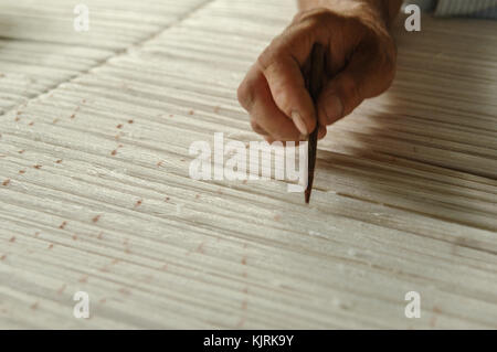 Hand mit einem Bleistift macht Flecken auf dem Teppich. Weberei und der Herstellung von handgefertigten Teppichen closeup Stockfoto