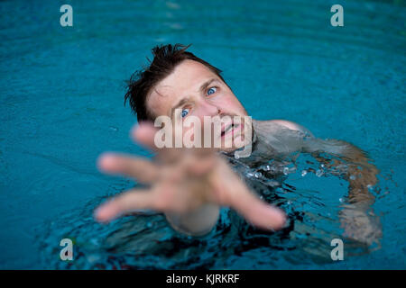 Ertrinken kaukasischen Mann im Schwimmbad um Hilfe zu bitten. Er streckte seine Hände in Angst. Stockfoto