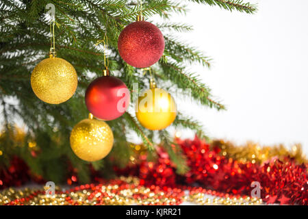 Weihnachtsschmuck, fünf goldene und rote Kugeln am Weihnachtsbaum Stockfoto