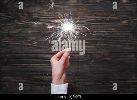 Neues Jahr Partei brennende Wunderkerze closeup in weiblicher Hand auf schwarzen Hintergrund. Stockfoto