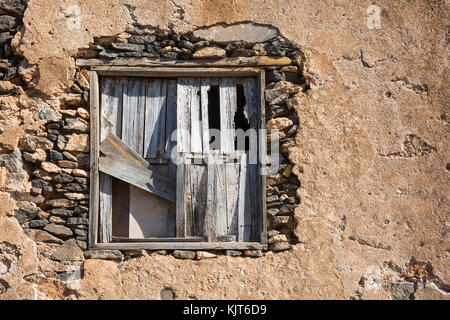 Eine alte Fensterrahmen mit Holzbohlen in einer alten Steinmauer gesperrt Stockfoto