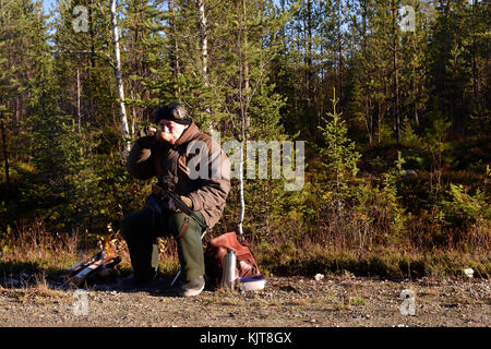 Elch Hunter auf einer Straße Tee trinken für Elche wartet sitzend, Bild aus dem Norden von Schweden. Stockfoto