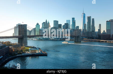 East River Ferry vorbei unter der Brooklyn Bridge mit dem Lower Manhattan Skyline im Hintergrund Stockfoto