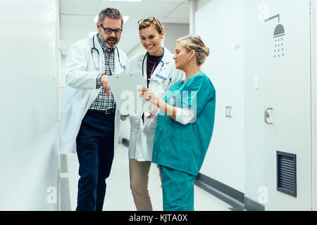 Gruppe von Ärzten und Krankenschwestern die Prüfung Ärztlicher Bericht des Patienten. Ärzte gemeinsam mit dem Patienten am Krankenhaus. Stockfoto