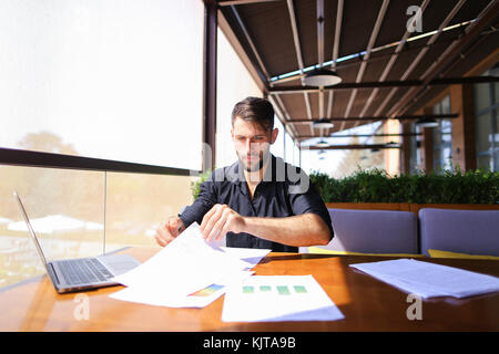 Büroangestellter sortieren Papiere auf dem Tisch in der Nähe der Räder. Stockfoto