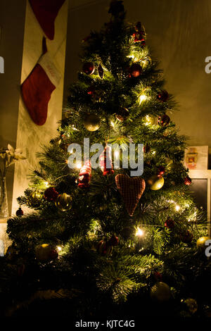 Ein schöner Weihnachtsbaum in eine kleine gemütliche Zimmer mit Strümpfen an der Wand. Stockfoto