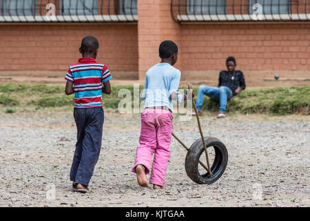 Zwei madagassische Jungen spielen Rollen Gummireifen mit zwei Sticks. Madagaskar, Afrika. Stockfoto