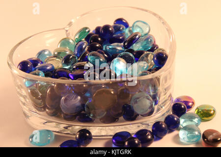 Verschiedene Schattierungen von blauen Glasperlen in Herzform Glas Container auf dem Boden Stockfoto