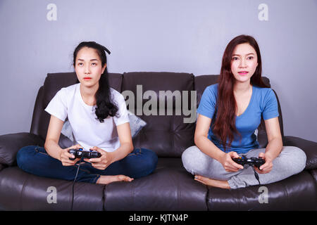 Zwei junge Frau mit Joystick spielen Video Game auf dem Sofa im Wohnzimmer zu Hause Stockfoto