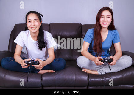 Zwei junge Frau mit Joystick spielen Video Game auf dem Sofa im Wohnzimmer zu Hause Stockfoto
