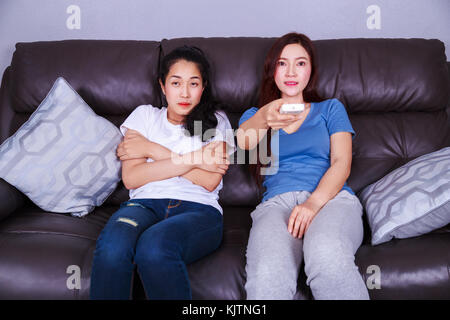 Zwei Frau hand Halten remote Klimagerät auf Sofa im Wohnzimmer zu Hause Stockfoto