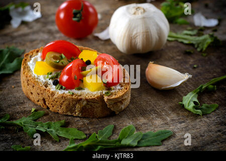 Selektiver Fokus auf die vegetarische Bruschetta mit Käse Sahne, Paprika, Oliven und Cherry Tomaten Stockfoto