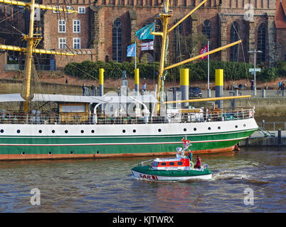 Bremen, Deutschland - 23. November 2017 - Rettungsboot Flinthörn an der Weser vorbei am Heck des ehemaligen Segeltrainingsschiffes Alexander von Humboldt wi Stockfoto