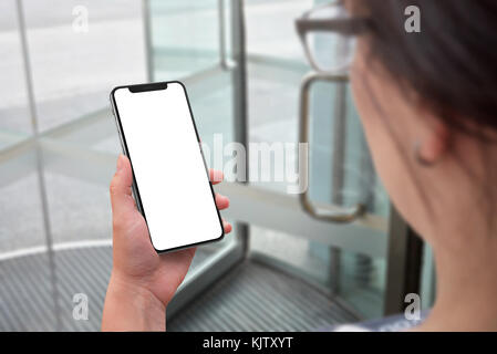 Frau mit modernen smart phone mit isolierten x gebogene für mockup. business center Tür im Hintergrund. Stockfoto