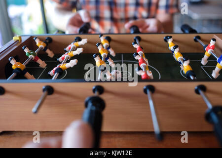 Mann spielt Tischfußball-Spiel close up mit seinen Freunden Stockfoto