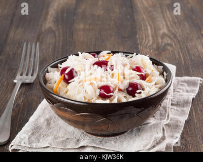 Traditionelle russische Vorspeise Sauerkraut mit Cranberry und Karotte in dunklen Handwerk Platte auf Braun rustikalen Holztisch. Fermentierter Kohl. Russische cuisin Stockfoto