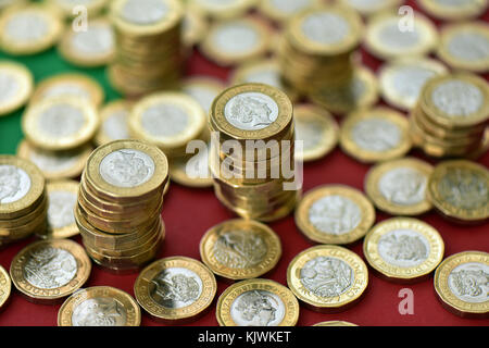 Eine große Anzahl von einem Pfund Münzen auf einer rot-grünen Hintergrund. Neue Pfund Münzen in großer Menge zufällig über einen farbigen Hintergrund verstreut. Stockfoto