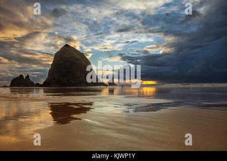 Clearing Sturm bei Sonnenuntergang über Cannon Beach, Oregon. goldenes Sonnenlicht gesehen wird durch die Wolken brechen. Stockfoto