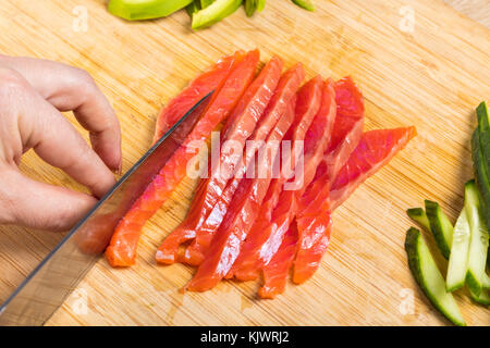 Der Küchenchef Schnitte roten Fisch mit einem Messer, Hände, Nahaufnahme Stockfoto