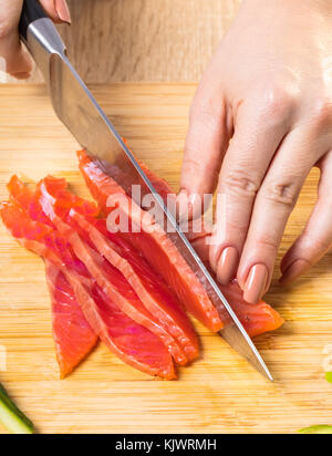 Der Küchenchef Schnitte roten Fisch mit einem Messer, Hände, Nahaufnahme Stockfoto