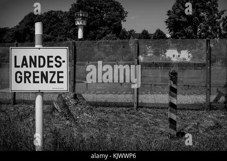 Das Schild sagt: "Landesgrenze. Die Bayerische Grenzpolizei hat 1989 die friedliche Revolution die Mauer zerfalle. Vor dem 9. November 1989 war der Eiserne Vorhang eine Todeszone in Deutschland: 245 Menschen, die aus der DDR fliehen wollten, wurden bei ihrem Versuch, diese unmenschliche Grenze zu überqueren, getötet. Mödlareuth, ein kleines Dorf, wurde durch diese Mauer in einem westlichen und östlichen Teil wie in Berlin getrennt. Aus diesem Grund wurde es als kleines Berlin bezeichnet. Das Foto wurde mit im Deutsch-Deutschen-Museum in Mödlareuth aufgenommen. Stockfoto