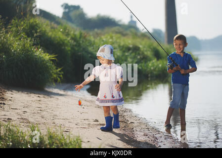 Jungen und Mädchen mit der Stange an der Küste des Flusses Stockfoto