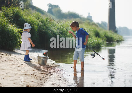 Jungen und Mädchen mit der Stange an der Küste des Flusses Stockfoto