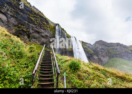 Reisen nach Island - Schritte in der Wasserfall Seljalandsfoss von seljalands Fluss in Katla Geopark zu Cave auf isländischen atlantischen Südküste im September Stockfoto