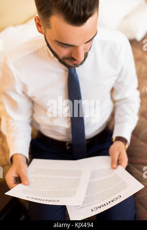 Hohen winkel Portrait von junge Unternehmer mit Dokumenten arbeiten sitzen auf Hotel auf Geschäftsreisen Stockfoto