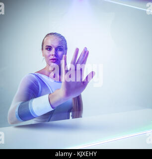Junge Frau berühren virtuelle leuchtende Anzeige Stockfoto