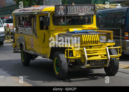 Eine gelbe Public Utility Jeepney Fahrzeug mit Passagieren in Olongapo City, Bataan, Philippinen angetrieben wird Stockfoto