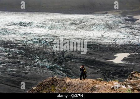 Ein einsamer Tourist nimmt ein Bild am Fuße des Skaftafelljökull Gletscher in Island Stockfoto