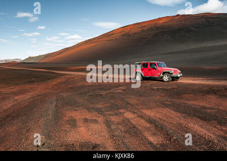Ein roter Jeep in einer Landschaft aus roten Kies und rote Erde auf der F902 Straße in Island Stockfoto