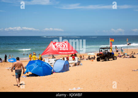 Leute, die sich am Newport Beach, den nördlichen Stränden von Sydney, Australien entspannen, mit Freiwilligen für Surferrettung und einem schattigen Zelt am Strand Stockfoto