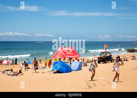 Leute, die sich am Newport Beach, den nördlichen Stränden von Sydney, Australien entspannen, mit Freiwilligen für Surferrettung und einem schattigen Zelt am Strand Stockfoto