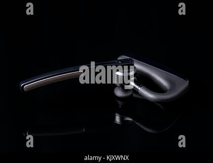 Business Bluetooth Headset auf schwarzem Hintergrund spiegeln. Nützlich für die geschäftliche Kommunikation Präsentation Hintergrund. Stockfoto