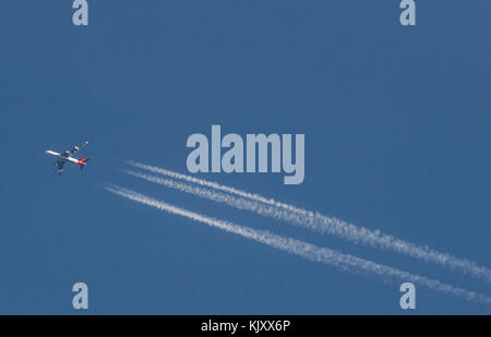 Am frühen Morgen Sonnenstrahlen fangen die Kondensstreifen eines vier Motor Passenger Jet. Stockfoto