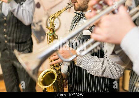 Musik, Show business, Orchester Konzept. Männer aus Jazz Band in herrlichem schwarzen Kostümen mit dünnen weißen Streifen gekleidet sind Spielen sax von Golden und Silber Trompete Stockfoto